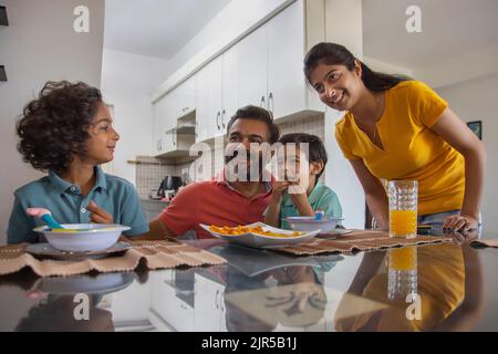 Ritratto di una famiglia nucleare che guarda via durante la colazione Foto Stock