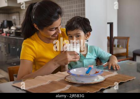 Ritratto della madre che nutre un bicchiere di latte al bambino Foto Stock