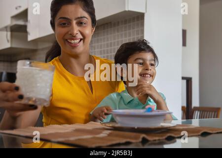 Ritratto della madre che nutre un bicchiere di latte al bambino Foto Stock