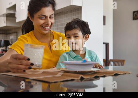 Ritratto della madre che nutre un bicchiere di latte al bambino Foto Stock