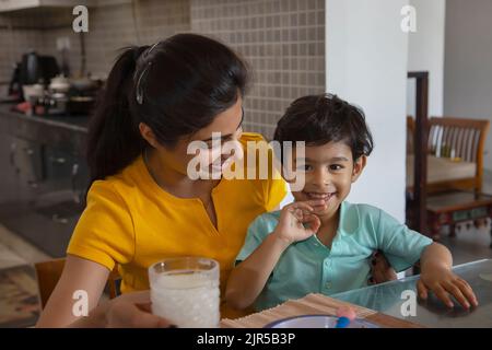 Ritratto della madre che nutre un bicchiere di latte al bambino Foto Stock