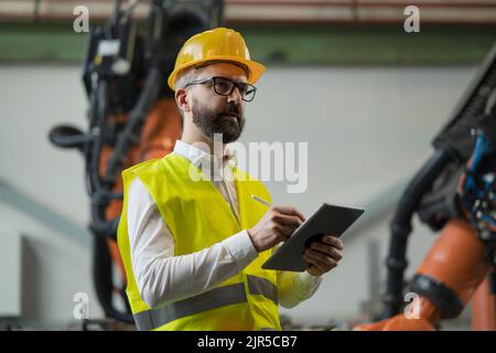 Ingegnere dell'automazione che tiene tablet digitali in fabbrica. Foto Stock