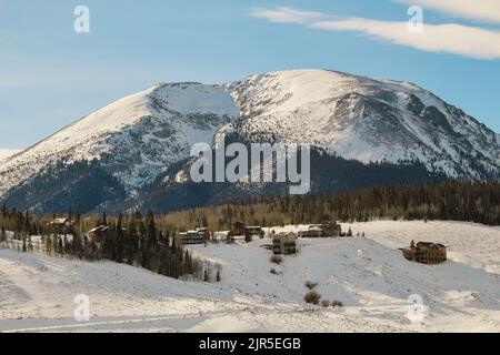 Numerose case sul fianco della collina nelle montagne innevate Foto Stock