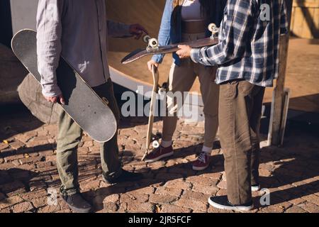 Immagine della sezione centrale di diversi amici femminili e maschili con skateboard in skate Park Foto Stock