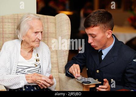 La veterana WAAF di 99 anni, Margaret 'Peggy' Terry, è presentata cinque shillings argentati in tempo di guerra e un'immagine incorniciata da William Anderson, specialista dell'aria di classe 1, alla Gwernllwyn Care Home, Gorslas, Galles, come un gesto di apprezzamento per il suo servizio quando, durante una recente conversazione, Ha scherzosamente menzionato a AS1 Anderson era ancora dovuta cinque scellini dopo aver lasciato la RAF, nel 1945. Data immagine: Lunedì 22 agosto 2022. Foto Stock