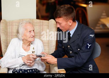 La veterana WAAF di 99 anni, Margaret 'Peggy' Terry, è presentata cinque shillings argentati in tempo di guerra e un'immagine incorniciata da William Anderson, specialista dell'aria di classe 1, alla Gwernllwyn Care Home, Gorslas, Galles, come un gesto di apprezzamento per il suo servizio quando, durante una recente conversazione, Ha scherzosamente menzionato a AS1 Anderson era ancora dovuta cinque scellini dopo aver lasciato la RAF, nel 1945. Data immagine: Lunedì 22 agosto 2022. Foto Stock