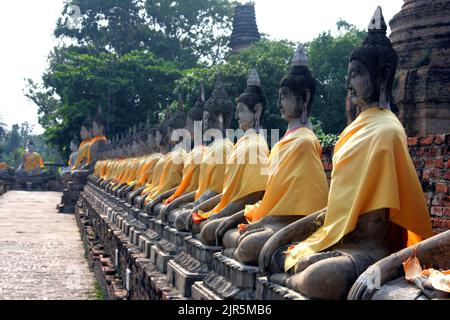 Una fila di immagini di Buddha intorno allo stupa centrale a Wat Yai Chai Mongkol, Thailandia Foto Stock