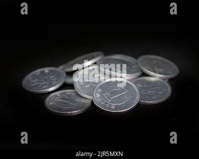 Un primo piano di un mucchio di monete d'argento di uno yen su sfondo nero Foto Stock