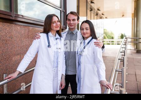 Un ritratto di seri e bei medici che indossano scrub e che tengono stetoscopi vicino alla clinica. Foto Stock