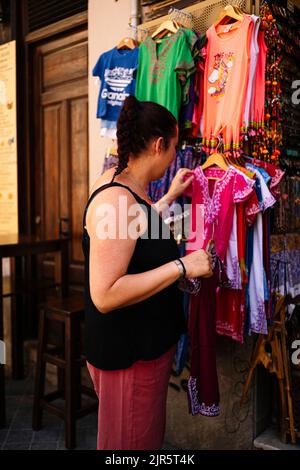 Una giovane donna che guarda i vestiti al mercato di strada. Foto Stock