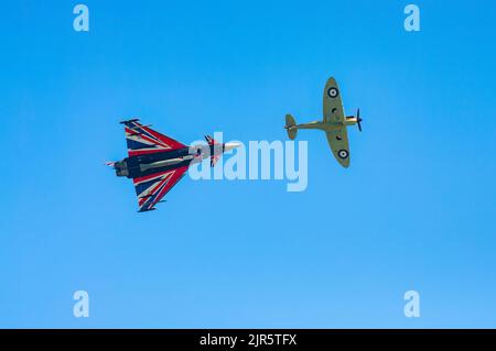 Uno Spitfire della seconda Guerra Mondiale e un moderno jet fighter Typhoon volano davanti all'annuale Eastbourne Airshow, uno dei più grandi eventi liberi del suo genere Foto Stock