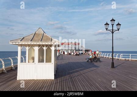 Sul molo Cromer con riparo e lampada con il teatro Pavilion sullo sfondo Foto Stock