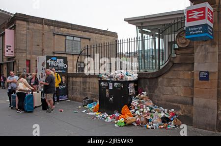 Stazione di Waverley, Edimburgo, Scozia, Regno Unito. 22nd agosto 2022. È stato un peccato per arrivare in vacanza e per essere accolto da un clima noioso e arido, anche se la temperatura è di 17 gradi centigradi, ma peggio ancora sono i bidoni dei rifiuti sui marciapiedi ammassati in alto e traboccanti di rifiuti scartati subito fuori dall'entrata della stazione ferroviaria. Ciò è dovuto al fatto che gli operatori della pulizia del Consiglio della città di Edimburgo sono il quinto giorno di undici giorni di sciopero sulla retribuzione. Credit: Arch White/alamy live news. Foto Stock