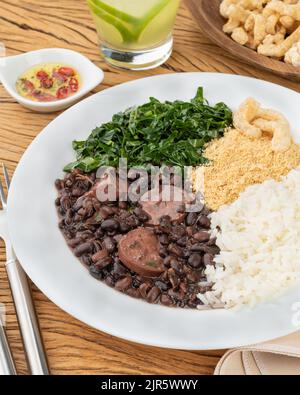 Tipica feijoada brasiliana con riso, pepe, farofa, kale, caipirinha e crackling. Foto Stock