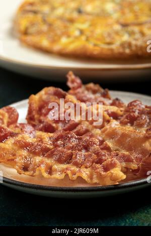 Primo piano di alcune fette croccanti di pancetta e tre uova fresche sullo sfondo. Foto Stock