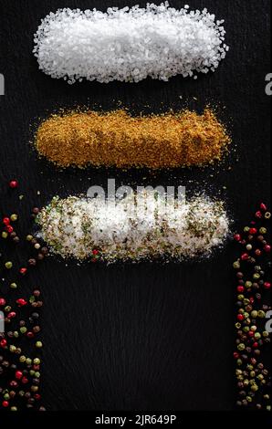 Assortimento di spezie macinate su fondo di pietra scura con spazio copia. Sale Svanstka, erbe provenzali, pepe e mescolare. Foto Stock