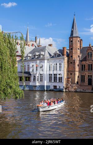 I turisti che si godono una gita guidata in barca intorno ai canali di Bruges, Belgio. Il Duc De Bourgogne Hotel & Restaurant è sullo sfondo. Foto Stock