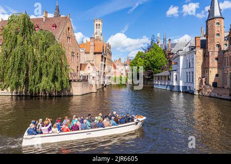 I turisti che si godono una gita guidata in barca intorno ai canali di Bruges, Belgio. Il Duc De Bourgogne Hotel & Restaurant è sullo sfondo. Foto Stock