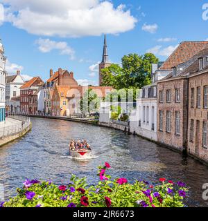 I turisti che si godono una gita guidata in barca intorno ai canali di Bruges, Belgio Foto Stock