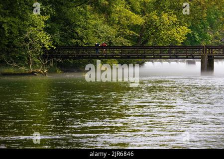 Due uomini in piedi sul ponte che attraversa il South Holston River, come la nebbia estiva delude. Foto Stock