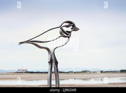 Il concetto di una spiaggia lontana, con un uccello metallico fabbricato in primo piano Foto Stock