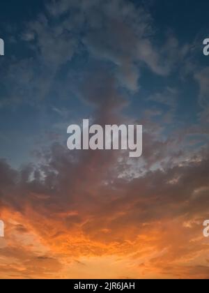 Bellissimo cielo al tramonto con colorate nuvole arancioni sull'orizzonte, sfondo celeste verticale Foto Stock