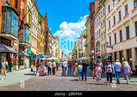 Szeroka strada piena di gente e case colorate nel centro storico di Torun, Polonia Foto Stock