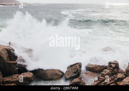 Grandi onde che si schiantano sulle rocce della costa Foto Stock