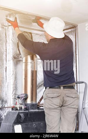 Installazione di lana minerale con foil intorno al camino per la protezione termica e temperature elevate per le pareti. Foto Stock