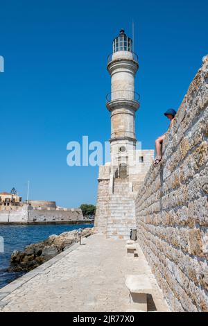 faro storico e mura del porto a la canea sull'isola greca di creta, donna seduta sulle mura dell'antico porto di la canea in grecia creta. Foto Stock