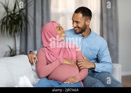 Amorevole nero incinta sposi islamici che si legano insieme a casa Foto Stock