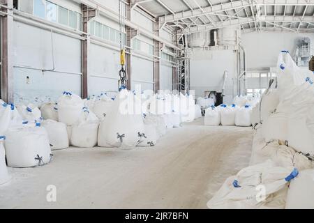 Spazioso impianto industriale o officina di manifattura moderna con mucchi di sacchi bianchi enormi e pesanti con materie prime Foto Stock