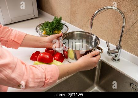 Donna versare acqua in pentola per la cottura del riso Foto stock