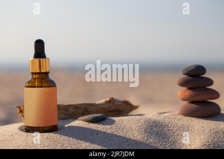 Prodotto cosmetico naturale organico, concetto di cura della pelle estivo. Bottiglia con gocciolatori sulla spiaggia, composizione naturale. Foto Stock