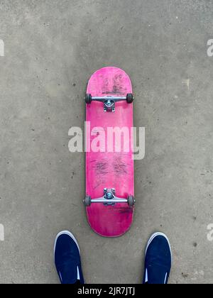 Scricchiolò su skateboard rosa che si posa su una superficie liscia in cemento presso lo skatepark locale Foto Stock