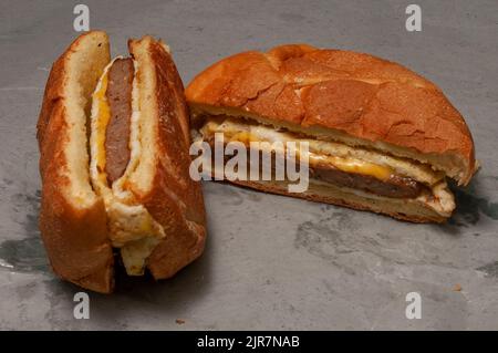 Abbondante sandwich con uova di salsiccia e biscotti al formaggio per la colazione Foto Stock
