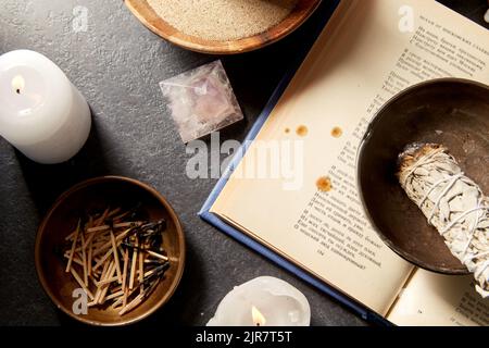 scienza occulta e concetto soprannaturale - libro magico, salvia bianca, candele brucianti e personale diverso per il rituale Foto Stock