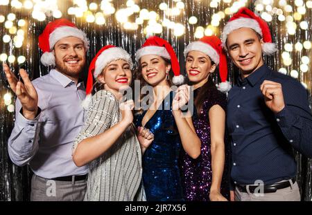 Happy amici in cappelli di Babbo Natale alla festa di natale Foto Stock