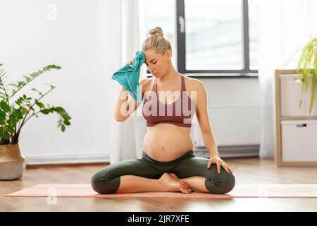 donna incinta stanca dopo lo yoga con asciugamano a casa Foto Stock