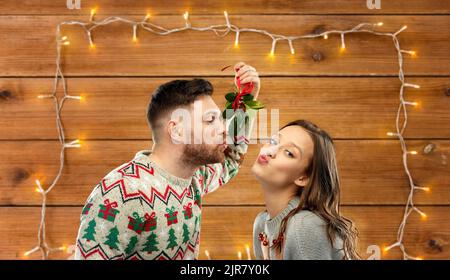felice coppia baciare sotto mistletoe il natale Foto Stock