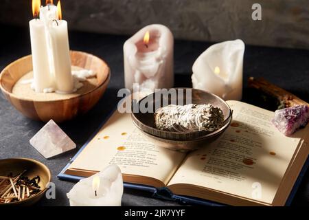 libro magico, salvia, candele bruciate e personale rituale Foto Stock