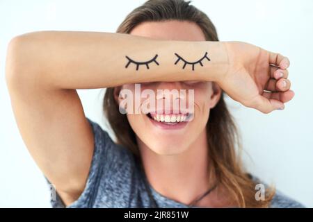 Scelgo di vedere cosa mi rende felice. Studio shot di un giovane che alza il braccio con illustrazioni di ciglia davanti agli occhi. Foto Stock