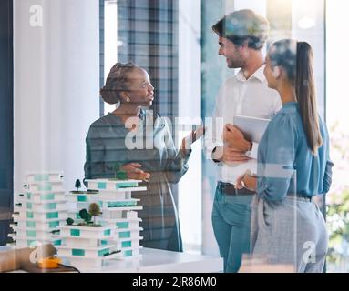 Architetti parlanti, ingegneri edili o progettisti che si incontrano, parlano e progettano la progettazione di strutture di modelli 3D residenziali. Gruppo o team diversi di Foto Stock