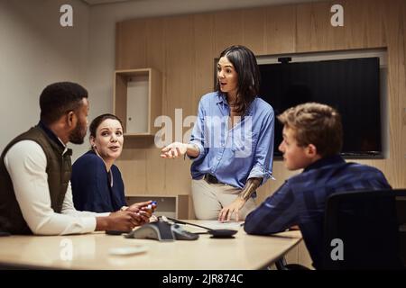 Prendendo preziosi contributi dal team. Una donna d'affari che dà una presentazione ai suoi colleghi in un ufficio. Foto Stock