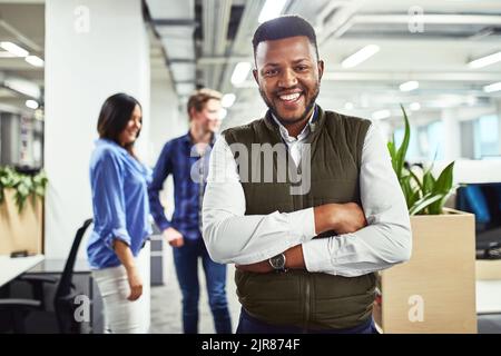 Ive ha avuto così successo in questa azienda. Ritratto di un giovane designer in un ufficio con i suoi colleghi sullo sfondo. Foto Stock
