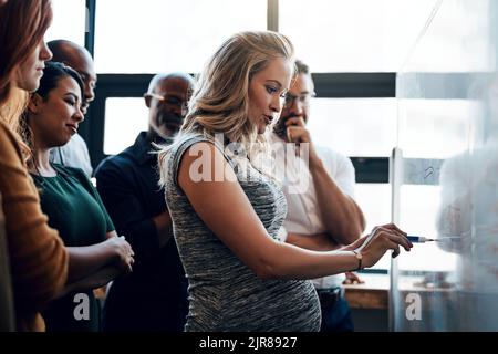 Mantenendoli aggiornati con tutti i nuovi sviluppi prima che lasci. Una donna d'affari incinta che dà una presentazione nella sala del consiglio. Foto Stock