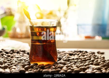 Caffè espresso brasiliano appena preparato in una tazza di vetro con chicchi tostati sullo sfondo della cucina Foto Stock