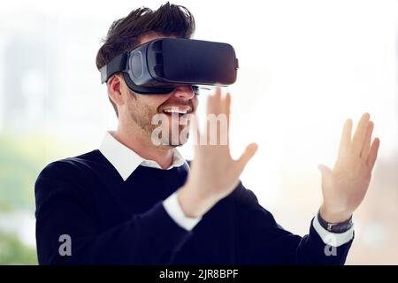 Nuove possibilità sono sempre a portata di mano: Un uomo d'affari che indossa un visore VR in ufficio. Foto Stock