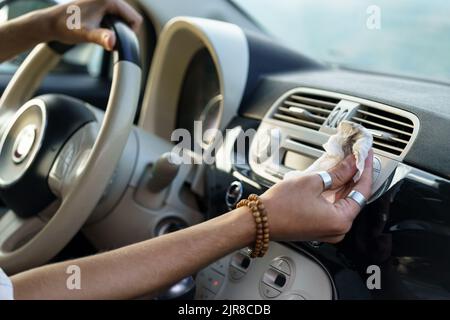 La mano del conducente rimuove la polvere dalla bocchetta di ventilazione del pannello dell'auto per un migliore funzionamento del sistema di ventilazione dell'aria Foto Stock