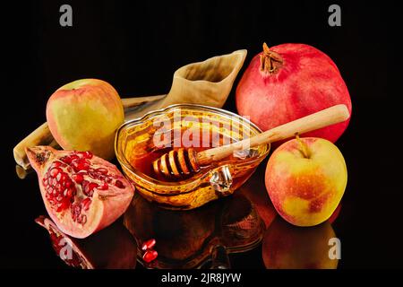 Rosh hashanah - concetto ebraico di vacanza di nuovo anno. Ciotola a forma di mela con miele, mele, melograni, shofar su sfondo nero con riflesso Foto Stock